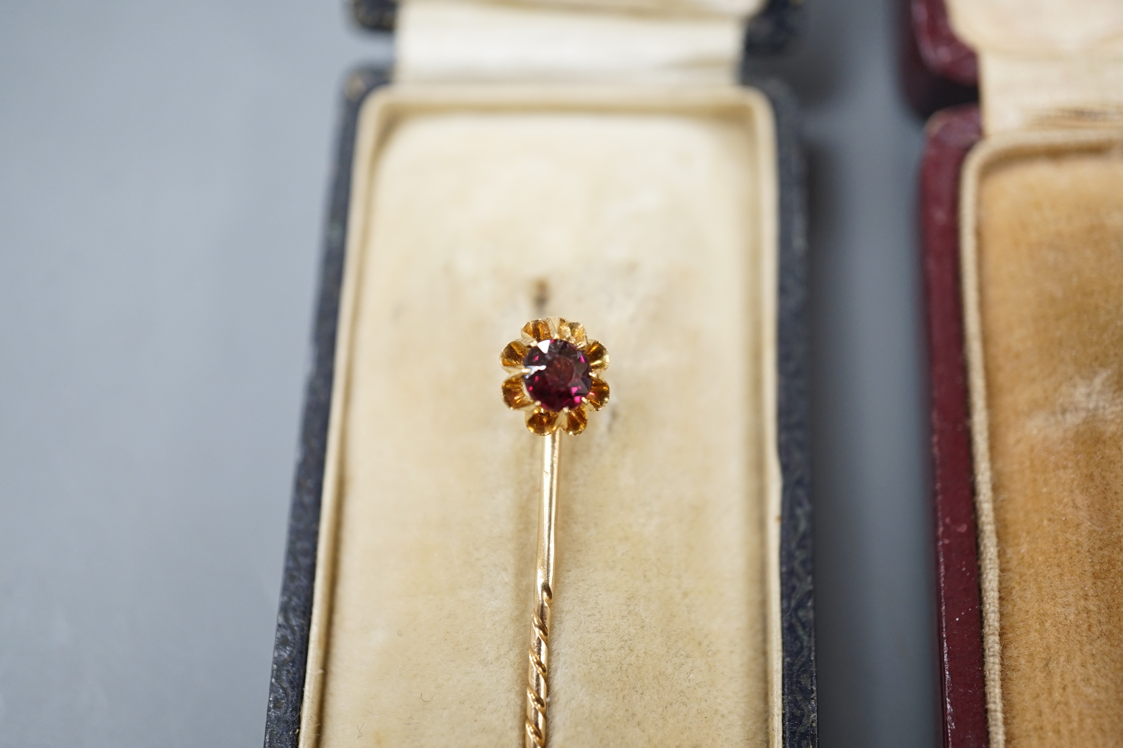 Three assorted early to mid 20th century yellow metal and gem set stick pins including diamond chip set horseshoe, 57mm and 15ct ruby and diamond chip and two other stick pins.